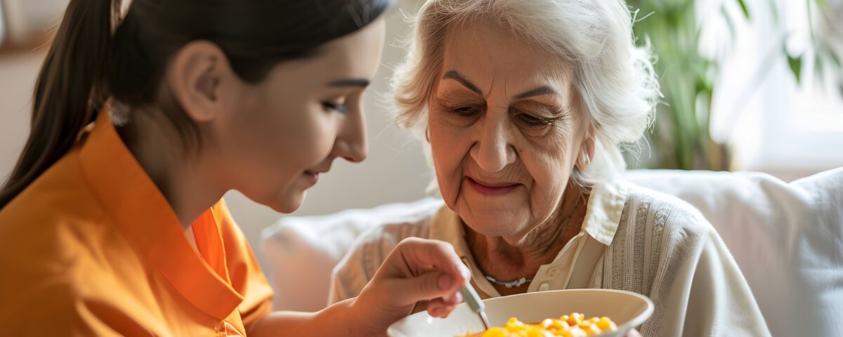 mulher ajudando idosa com disfagia a comer